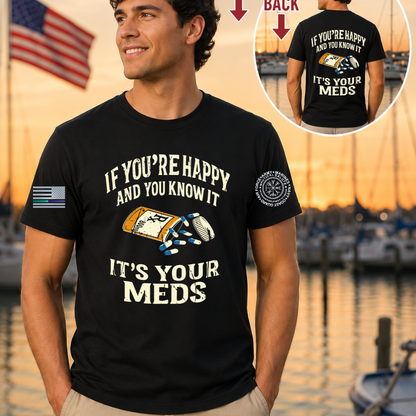 Man wearing a black t-shirt with a humorous graphic and text, standing by a waterfront with an American flag in the background.